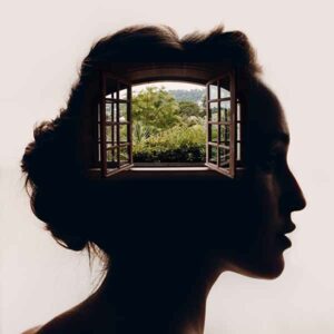 Silhouette of a woman's head with and window in it showing the outside world.